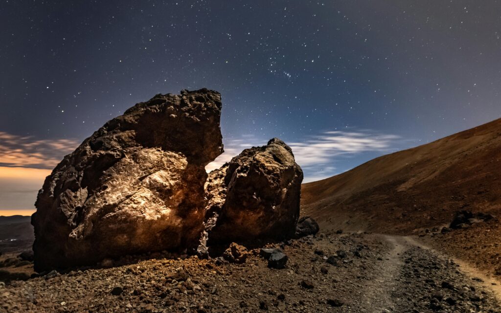 Night view of rocky desert landscape under a starry sky in Tenerife, Spain.